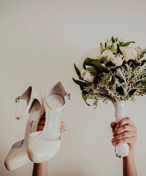 Décolleté da sposa chiare tenute in mano accanto al bouquet — Tulle Calzature, Torino